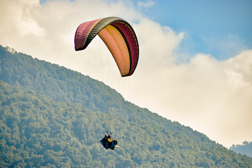 Fethiye, Mugla / Turkey August 28 2020: Paragliding in the sky. Paraglider flying over the sea with mountains at sunset. Aerial view of Oludeniz