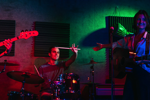 Hitting the Note: Music band singing and playing instruments on an indoor stage with colored lighting during a live concert