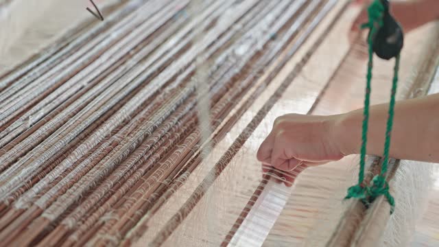 Unrecognizable female's hand weaving Thai silk panning shot close up