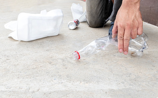 Man keep compressed plastic bottle on the floor