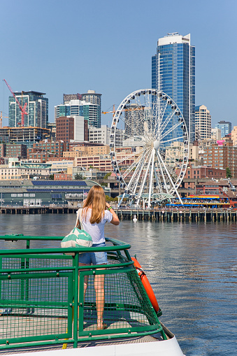 Bainbridge Island, Washington - August 13th 2015, A lady taking a picture Seattle Waterfront on the deck of Washington State Ferry between Bainbridge island and Seattle Washington.