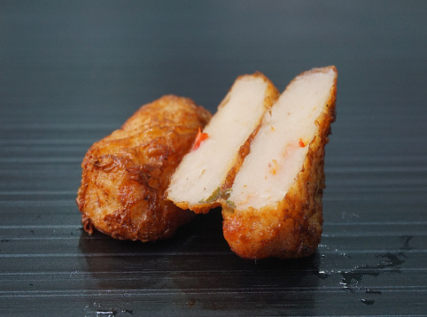 deep fried pork fish meat roll wrapped with bean curd skin ngohiang in plate on dark grey wood table asian dim sum halal food restaurant cuisine banquet menu for cafe