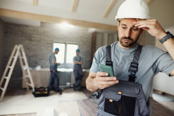 istock Displeased manual worker using cell phone during home renovation process. 2075081668