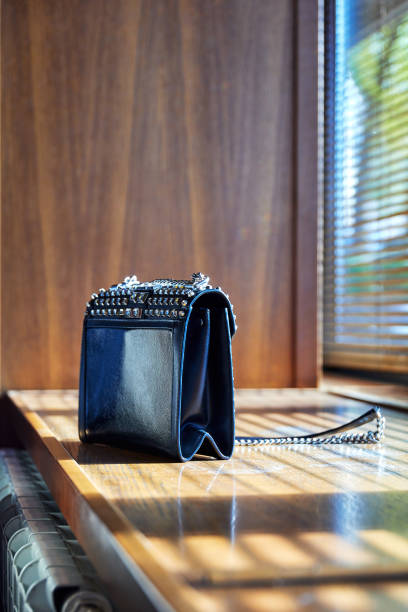a clutch or a woman's handbag on the windowsill with shadows from the blinds