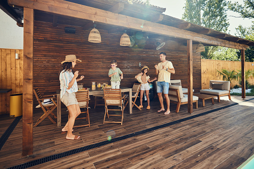 Happy parents and their kids having fun while dancing during a summer party on a patio.