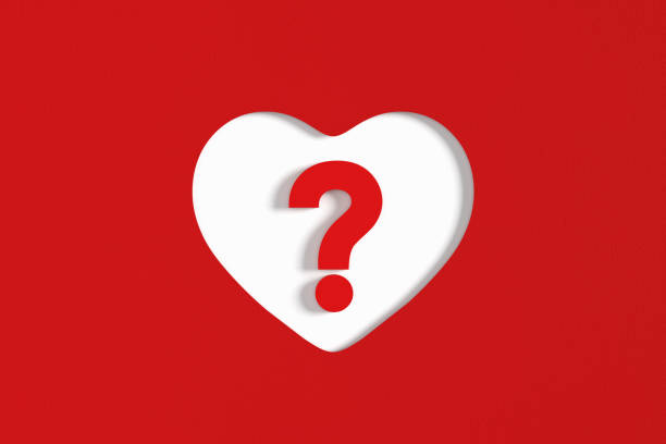 istock Question mark symbol in a heart shaped hole on red paper background. 2075106473