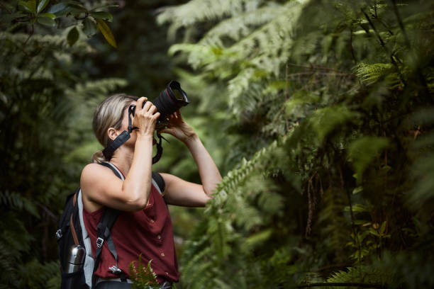 Young female hiker taking a photo in the forest.