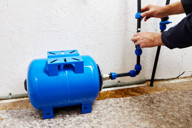 istock Plumber connects diaphragm pressure accumulator storage tank to home water supply system using HDPE pipes connected by compression fittings. 2075178823