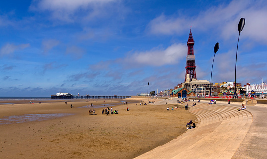 View along the beach in the centre of Blackpool Lancashire UK. Blackpool Tower can be seen in the distance and people can be seen on the beach.
