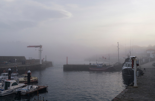 View of the port of the village of Comillas in Cantabria with a lot of fog at sunset.