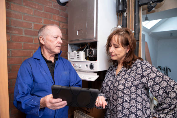 Qualified gas boiler engineer explaining a job report to a concerned customer Homeowner dealing with small home insurance issues: Mature female homeowner reviewing a gas engineer's report on a digital tablet. They are standing in a garage. qualified report stock pictures, royalty-free photos & images