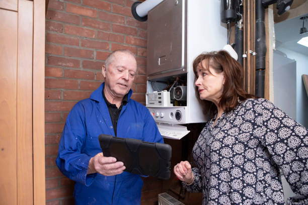 Qualified gas boiler engineer explaining a job report to a concerned customer Homeowner dealing with small home insurance issues: Mature female homeowner reviewing a gas engineer's report on a digital tablet. They are standing in a garage. qualified report stock pictures, royalty-free photos & images