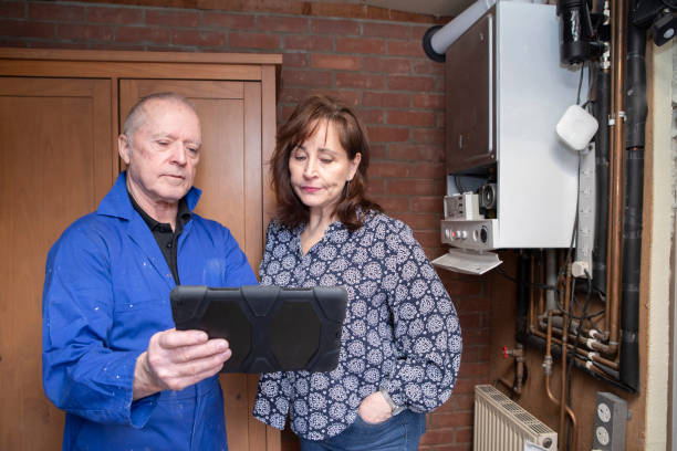 Qualified gas boiler engineer explaining a job report to a concerned customer Homeowner dealing with small home insurance issues: Mature female homeowner reviewing a gas engineer's report on a digital tablet. They are standing in a garage. qualified report stock pictures, royalty-free photos & images