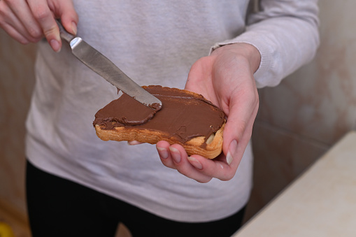 the girl spreads chocolate butter on bread with a knife