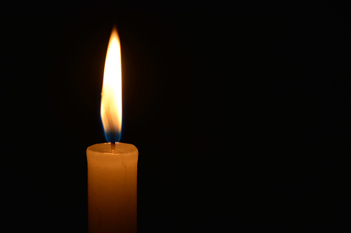 A closeup of a lit candle in the dark