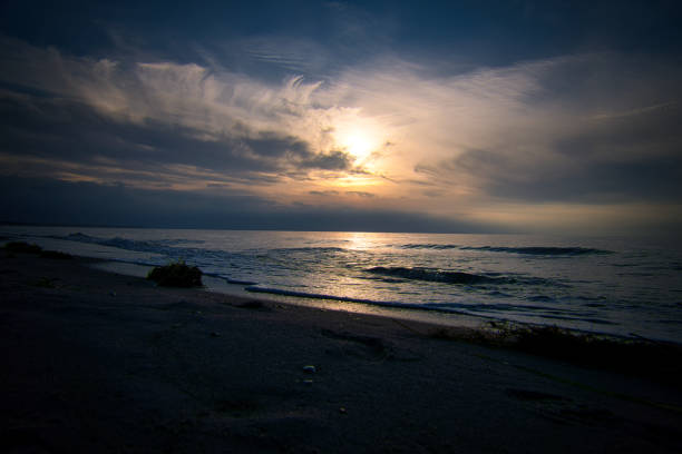 Sunset, illuminated sea. Sandy beach in the foreground. Light waves. Baltic Sea. Landscape on the coast