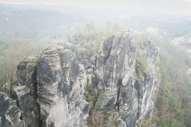 Jagged rocks at the Basteibridge. Wide view over trees and mountains. National park in Germany