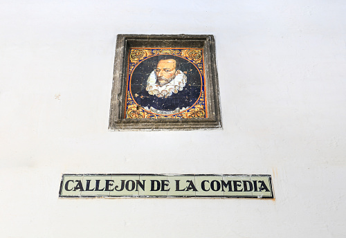 Sanlucar de Barrameda, Cadiz, Spain- October 3, 2023: Name of Callejon de La Comedia street on tiled plaque and Miguel de Cervantes portrait