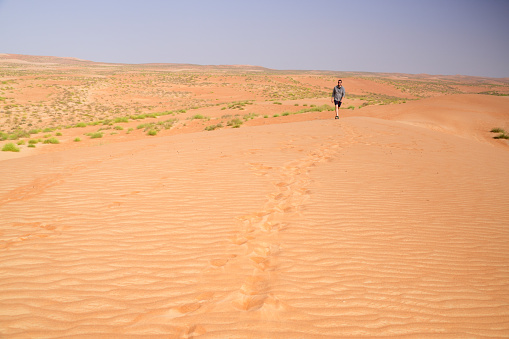 a man with camels in the sand dunes desert of Libya.