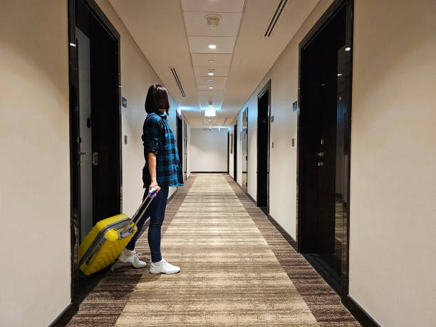 istock Woman walks along a hotel corridor with a suitcase 2075257294