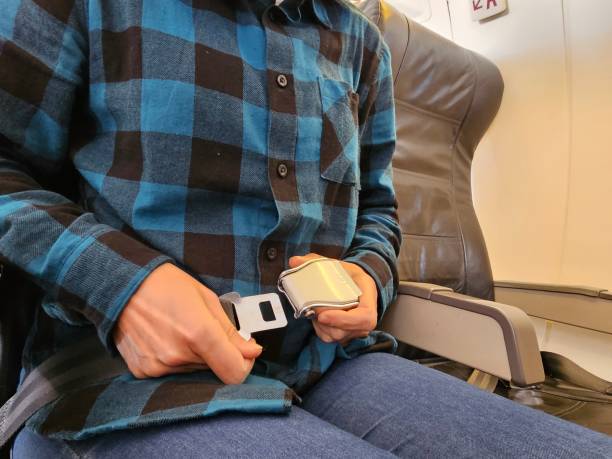 istock Passenger fastening seat belt while sitting on airplane for safe flight 2075270699