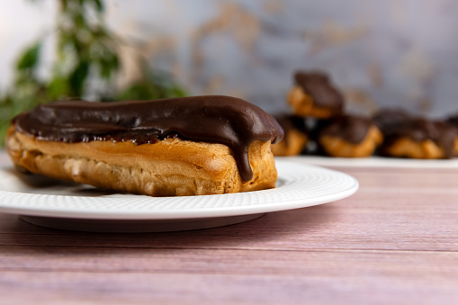 French ecler with chocolate. Traditional french dessert eclair. Chocolate cake with cream