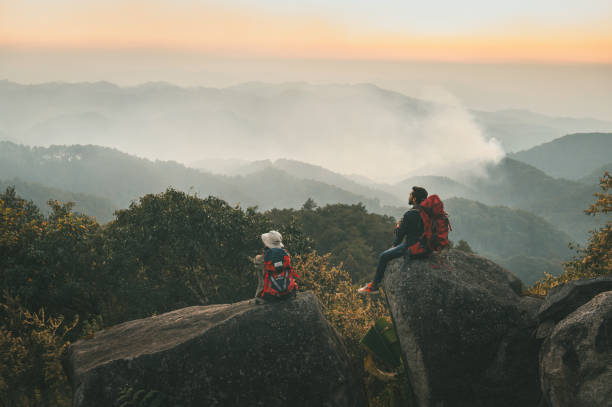 Two people are sitting on a rock in the mountains