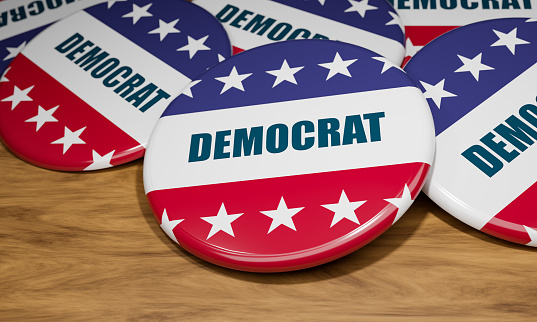 Close-up democrat badges with the national flag of the United State and in the word Democrat in capital letters. US election campaign button laying on a wooden table. Politics and government, democratic party, election concept. 3d illustration.