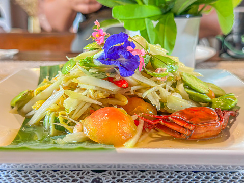 Green papaya salad or som tam with crab on white plate in restaurant,Thai food style Thailand.