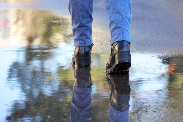 istock Female legs in boots on a street with puddles 2075308234