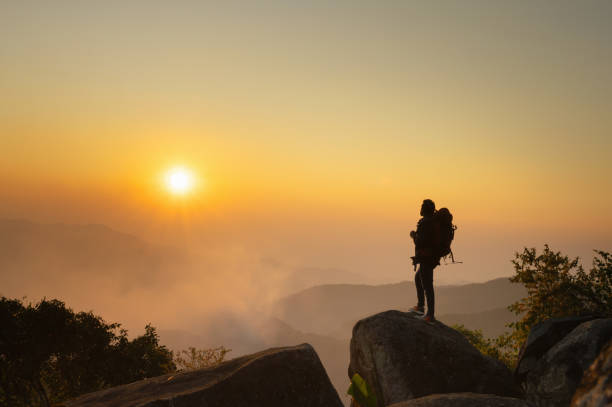 istock man is standing on mountain top, looking out at the sunset 2075322785