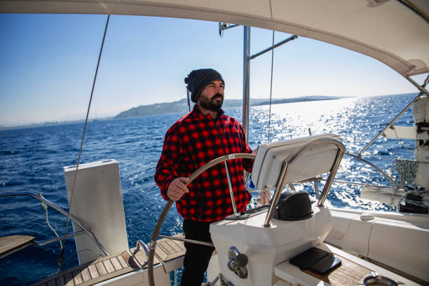 mature men steers sailboat at sea - yacht nautical vessel autopilot sailing imagens e fotografias de stock