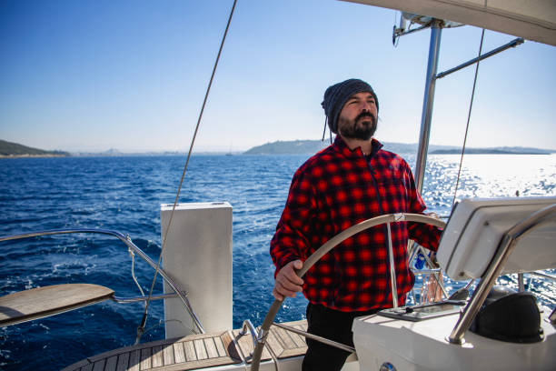 mature men steers sailboat at sea - yacht nautical vessel autopilot sailing imagens e fotografias de stock