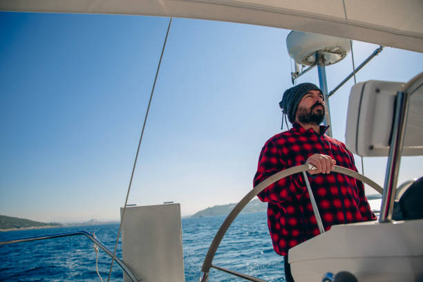 mature men steers sailboat at sea - yacht nautical vessel autopilot sailing imagens e fotografias de stock