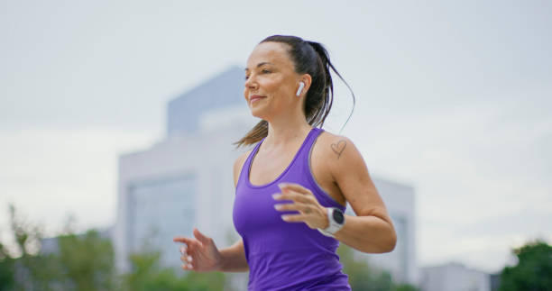 mulher branca em forma correndo na cidade no final da tarde - distance running audio - fotografias e filmes do acervo