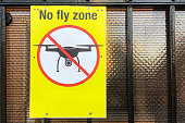 No fly zone yellow sign on fence. No drone zone sign