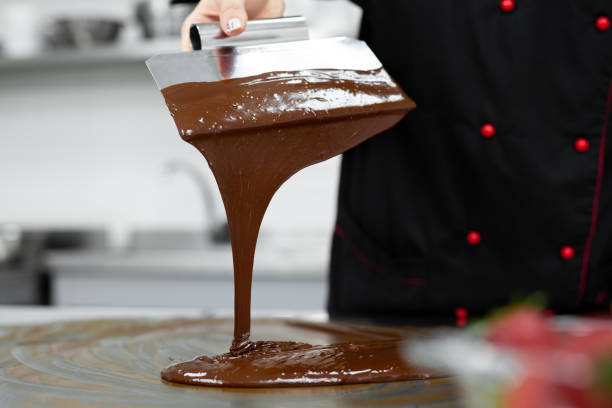 istock Close-up of a pastry chef using spatulas tempering molten chocolate. 2075356317