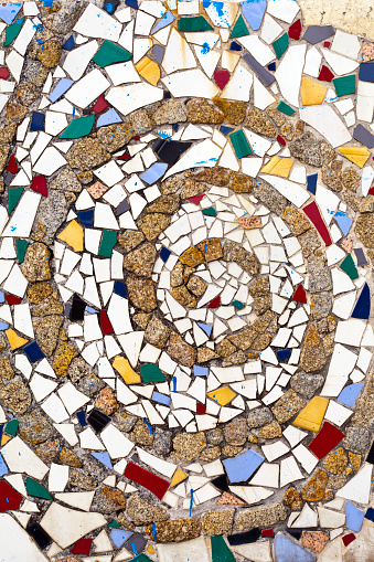 Multi colored tiles  and stone pattern, wall or flooring decoration, spiral shape . Traditional trencadis decoration, construction material, full frame image suitable for backgrounds . Spain.
