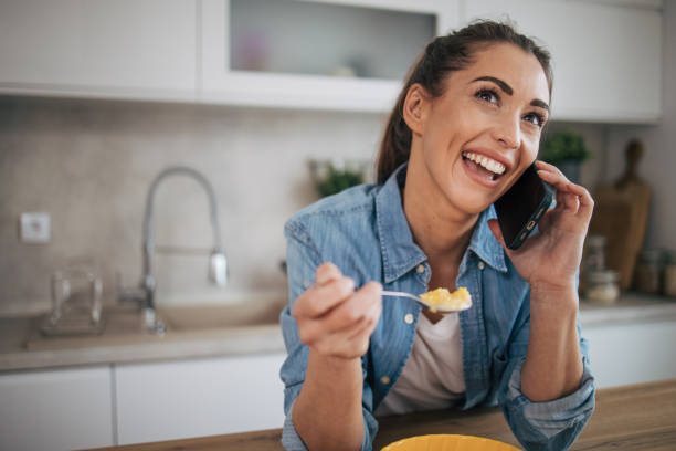 istock Young woman using the mobile phone while eating cereal with milk 2075378873