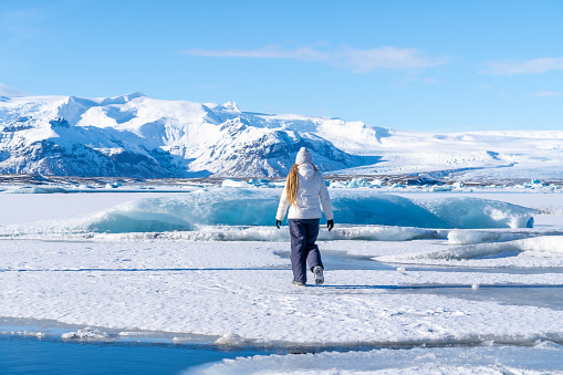 Woman walking on the ice of the frozen Jokulsarlon lake on vacation in Iceland