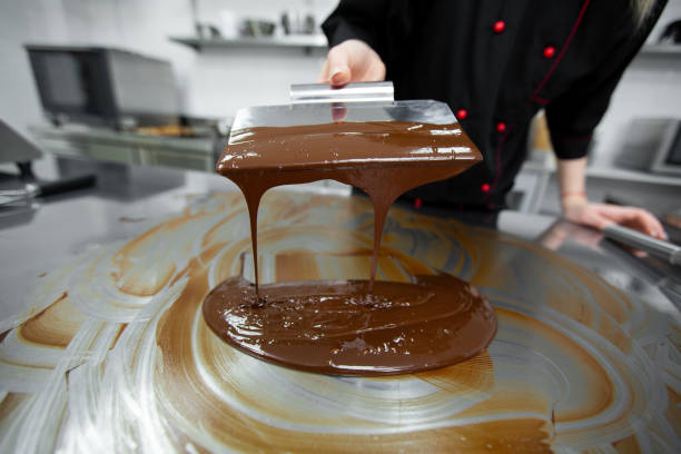 istock Close-up of a pastry chef using spatulas tempering molten chocolate. 2075386131