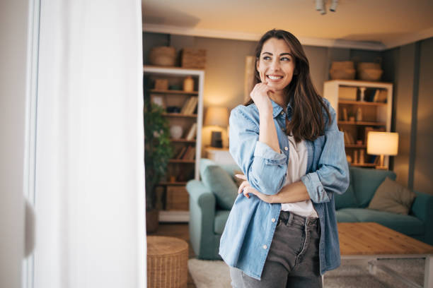 istock Beautiful young woman enjoying the view while standing by the window 2075386476
