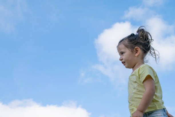 A little girl lights up summer with a radiant smile, captured on a sunny day under a blue sky. Childhood happiness is reflected in her face, transmitting the joy of the summer moment.