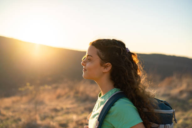 istock Teenage girl with backpack standing on mountain during sunset 2075392345