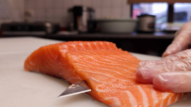 istock An experienced Japanese chef accurately cuts juicy salmon into thin slices, orange-colored salmon, the chef creates exquisite slices of fresh salmon, embodying the essence of culinary excellence 2075403642