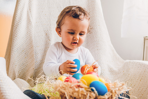 A little boy playing and enjoying with a basket of Easter eggs at home. Preparing the family for Easter.