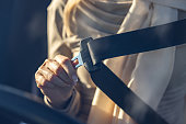 Close-up of a woman fastening her seatbelt in a car