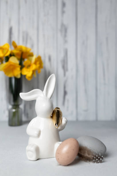 istock Easter bunny and eggs on table, bouquet of daffodils on background. Copy space 2075411717