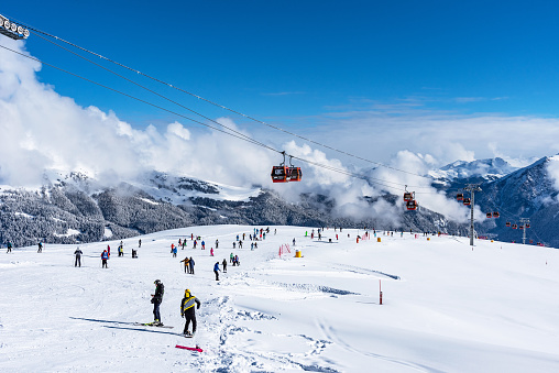 Arkhyz, Russian Federation - January 23, 2023: Tourists ski and snowboard at the Arkhyz resort. Ski lifts in the Arkhyz resort on a sunny day in winter.