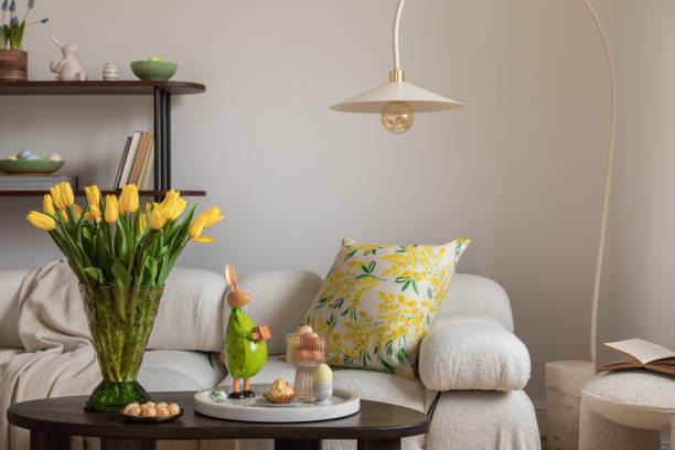 istock Sunny and design interior of living room with easter decorations, tulips, modular sofa, shelf, pillows and elegant accessories. Home decor. Easter holidays. 2075434072